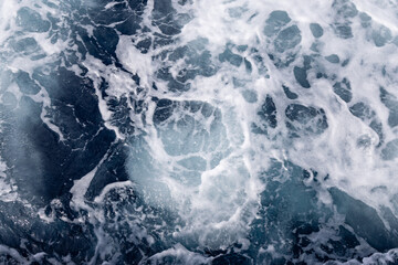 splash of ship water trails cutting through calm sea from top