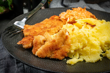 Breaded chicken breast fillet served with boiled potatoes and salad.