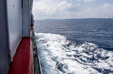 Obraz premium serene sea horizon with ship water trails cutting through sea water under bright blue sky