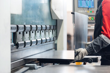 Worker operating metal press machine in industrial factory setting