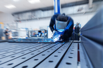 Industrial factory scene: male welding metal in manufacturing setting