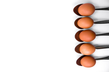 five brown eggs in spoons on a white background, top view. The minimalistic and aesthetic design is suitable for advertising cooking, healthy eating and farm products.