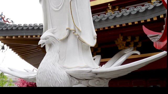 Tilt-Up Slow Motion of White Guan Shi Yin Statue in Front of a Traditional Asian Pagoda Building at Pantjoran PIK, Jakarta - Indonesia