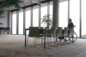 A director in a wheelchair sitting alone in an empty office, deeply reflecting on business strategies and decisions, contemplating the path forward with focused determination.