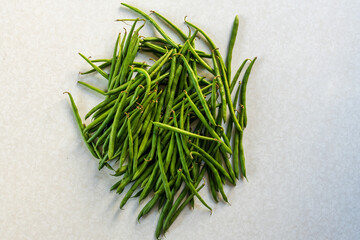 Stack of fresh green long beans on a marble surface. Top view