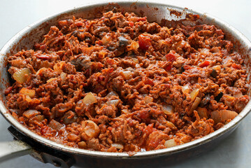 Homemade minced lamb dish cooked with onion, tomato and aubergine in a frying pan