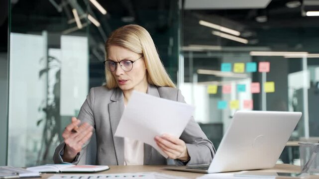 Confused distracted businesswoman having difficulty with paper work in office. Puzzled female employee is busy with accounting, having problems with task of financial report while reviewing documents