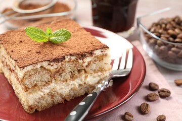 Plate with delicious tiramisu, mint and coffee beans on wooden table, closeup