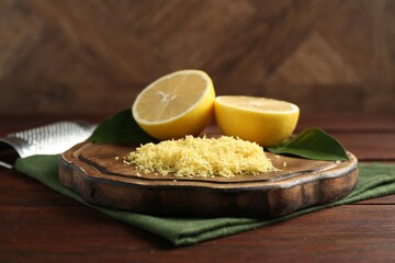 Lemon zest, grater and fresh fruit pieces on wooden table