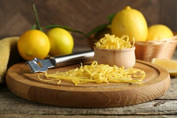 Lemon zest, zester tool and fresh fruits on wooden table, closeup