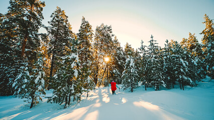 A tourist girl with a backpack walks through a snowy winter forest