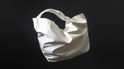 Crumpled white fabric tote bag floating against a black background.