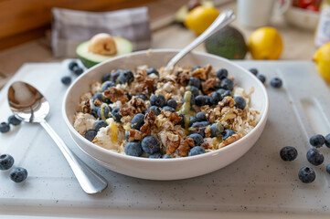 Healthy protein breakfast bowl with cottage cheese, oats, walnuts, blueberries and honey in the kitchen