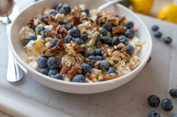 Healthy protein breakfast bowl with cottage cheese, oats, walnuts, blueberries and honey in the kitchen