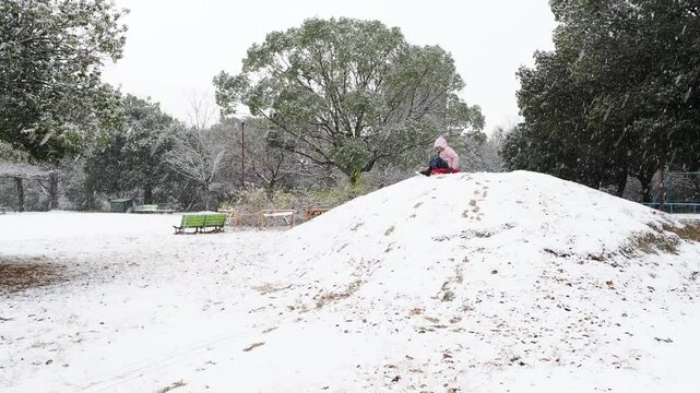 冬の公園で楽しく雪遊びしている小学生の女の子の様子
