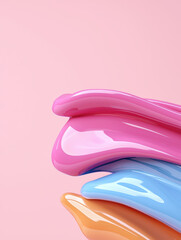 Colorful, glossy, layered materials create vibrant composition against soft pink background, evoking sense of playfulness and creativity