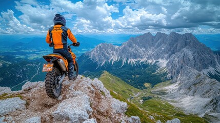 Fototapeta premium Motorcyclist on mountaintop overlooking valley.