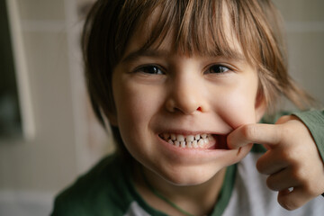 Cheerful funny toddler cute boy is showing funny faces, fooling around, joking, aping with silly...