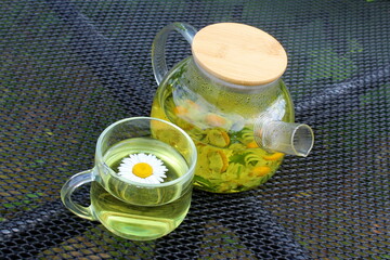 There is a glass teapot with chamomile tea on the table.