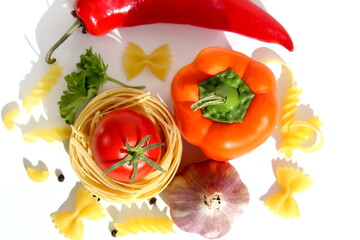 Fresh ripe harvest of vegetables lies on white isolated background with dry pasta before cooking.