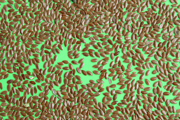 Scattered flax seedFlax seeds lie scattered on an isolated green background.s lie on a green background.