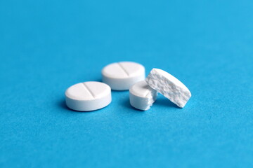 There are white round tablets on a blue background.