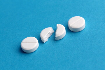 White broken pills lie on a blue background.	