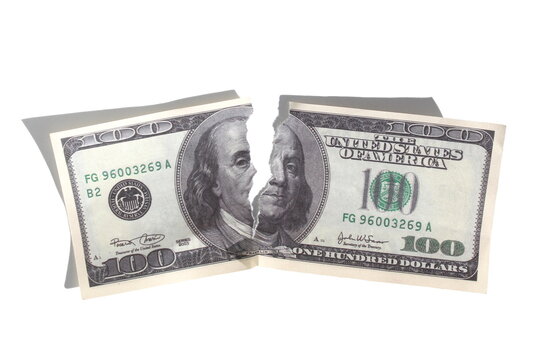 A torn hundred dollar bill lies on a white background.