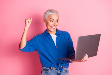 Photo of lucky positive woman wear blue shirt winnin game modern device empty space isolated blue color background