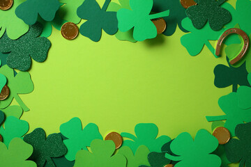 St. Patrick's Day frame of green shamrock leaves, gold coins, and horseshoe on light green...