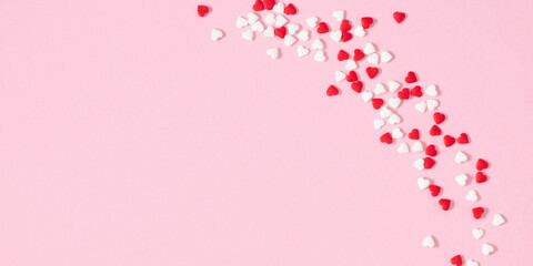 Happy Valentine's Day sweets. Border pattern of candy hearts sprinkles on pale pink background, mother's day concept. Love, romance. Flat lay, banner