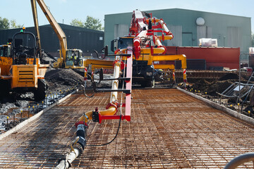 Construction site with equipment pouring concrete and preparing ground for a building at midday