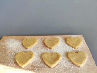 Freshly prepared heart-shaped cookies on a floured board