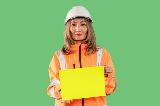 Construction worker holding blank sign in bright safety gear against green background - Powered by Adobe