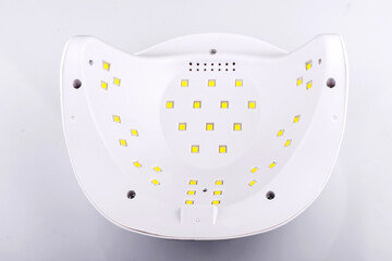 UV LED nail lamp for manicure lies on white table. Infrared induction helps to dry nails quickly