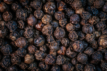 A close-up macro image of whole black peppercorns, showcasing their rich texture and dark brown tones. Perfect for culinary and spice-related themes.