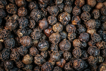 A close-up macro image of whole black peppercorns, showcasing their rich texture and dark brown tones. Perfect for culinary and spice-related themes.