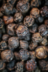 A close-up macro image of whole black peppercorns, showcasing their rich texture and dark brown tones. Perfect for culinary and spice-related themes.