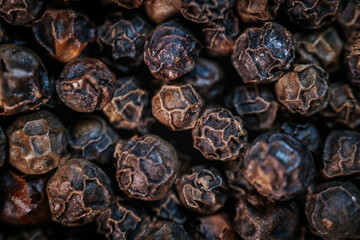 A close-up macro image of whole black peppercorns, showcasing their rich texture and dark brown tones. Perfect for culinary and spice-related themes.