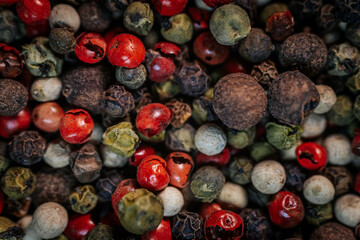 Close-up macro of colorful peppercorn mix featuring black, white, red, and green peppercorns. A vibrant blend of textures and spices, ideal for culinary and seasoning themes.