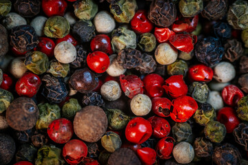 Close-up macro of colorful peppercorn mix featuring black, white, red, and green peppercorns. A vibrant blend of textures and spices, ideal for culinary and seasoning themes.