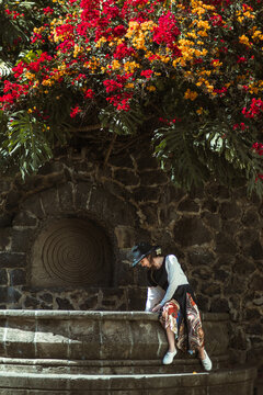 Girl sitting in a stone fountain playing with water, located in a magical town called Malinalco, State of Mexico.