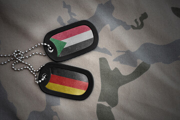 vintage army blank, dog tag with flag of sudan and germany on the khaki texture background....
