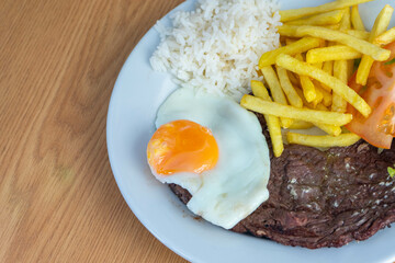 Portuguese bitoque dish: tender steak topped with a sunny-side-up egg, served with crispy fries and fresh salad. Traditional comfort food in Portugal.