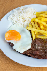 Portuguese bitoque dish: tender steak topped with a sunny-side-up egg, served with crispy fries and fresh salad. Traditional comfort food in Portugal.