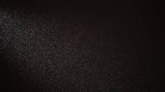 White particles are slowly falling diagonally on a black background, creating a mesmerizing visual effect suitable for overlay or screen blend modes