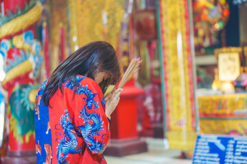 Asian woman light incense to worship deities and pray for blessings at a shrine in Chinese New Year.