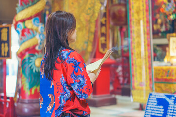 Asian woman light incense to worship deities and pray for blessings at a shrine in Chinese New Year.