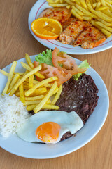 Traditional Portuguese meal with roasted pork loin and fries, and bitoque with a fried egg, served in a cozy restaurant setting. Authentic Portuguese cuisine at its best.