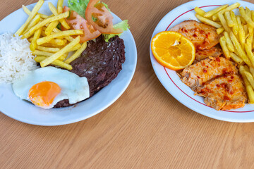 Traditional Portuguese meal with roasted pork loin and fries, and bitoque with a fried egg, served in a cozy restaurant setting. Authentic Portuguese cuisine at its best.